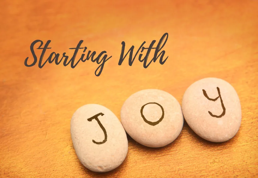 Smooth stones spelling the word JOY beside script lettering that reads Starting With on a warm background