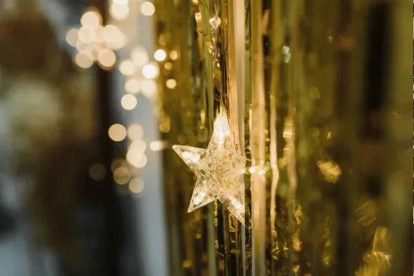 A glowing star light shining warmly among golden bokeh and tinsel